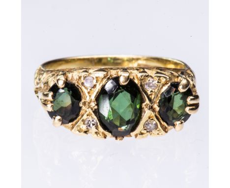 A GREEN TOURMALINE RING, the three graduating oval cut green tourmalines set in a heavily pierced scroll detail mount. Stampe