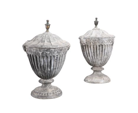 A PAIR OF GEORGE III LEAD URNS, C.1800, the fluted bodies with ribbon-tied swags and masks. 57cmFinials sit loosely. Base of 