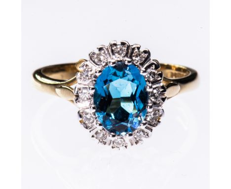 A 9CT YELLOW GOLD, BLUE TOPAZ AND DIAMOND CLUSTER RING, the oval cut blue topaz set within a surround of brilliant cut diamon