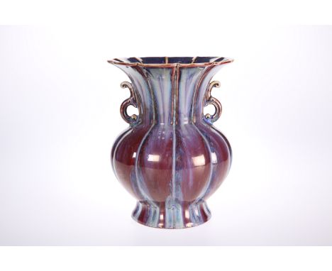 A CHINESE PORCELAIN TWIN-HANDLED VASE IN A STREAKY OX BLOOD GLAZE, with flared rim and segmented moulded body, impressed seal