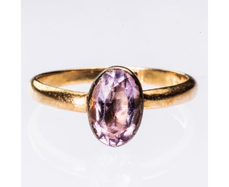 AN 18CT YELLOW GOLD AND PINK STONE RING, the oval cut pale pink stone set in closed back mount on simple tapering band. Stamp