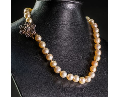 A CULTURED PEARL NECKLACE, the thirty-nine uniform cultured pearls each strung knotted onto a flower head shaped clasp set wi