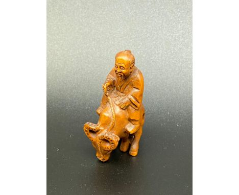 A Japanese hand carved netsuke of a elderly gentleman riding an ox. [5cm in length] 