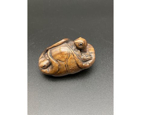 A Japanese hand carved netsuke of two turtles curled up in a lily pad. Both have black bead eyes and signed. [4.5cm in length