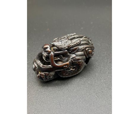 A Japanese hand carved netsuke of a curled up dragon. Designed with black bead eyes and signed by the artist. [5cm in length]