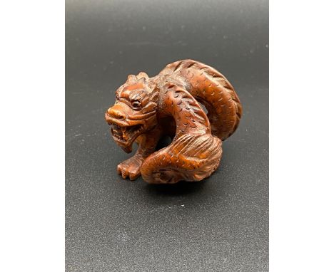 A Japanese hand carved netsuke of a curled up dragon. [4cm in length] 