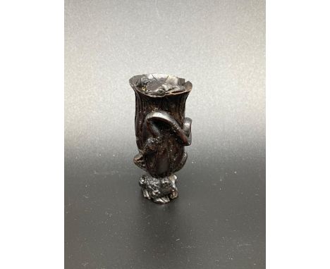 A Japanese hand carved netsuke of a flower sat upon a toads back. The flower is designed with a snake, snail and another toad
