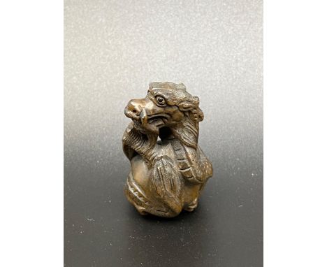 A Japanese netsuke of a dragon curled up round a ball. [5cm in length] 