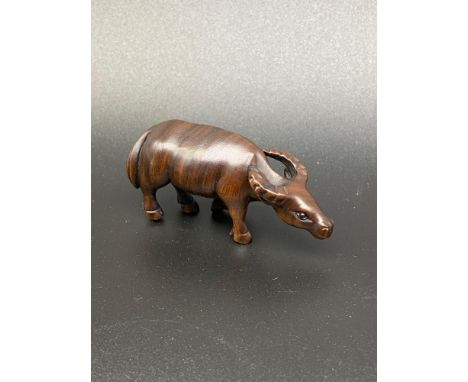 A Japanese hand carved netsuke of an ox. Designed with black bead eyes and signed. [6cm in length] 