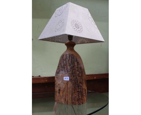 A rough natural wood based table lamp, with decorative pierced shade