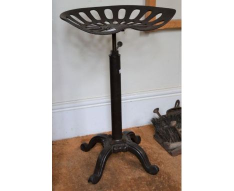 A vintage tractor seat mounted on an adjustable cast base to form a stool