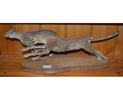 A model of two racing cheetah on wooden plinth base