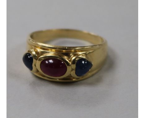 A yellow metal, cabochon ruby and sapphire three stone dress ring, size R.