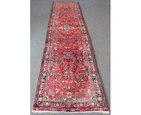 A Sarouk runner, north West Persia - with a central ivory four-pointed floral medallion on a raspberry red field with all ove
