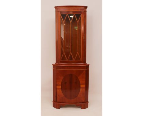 A bow-fronted yew veneered corner cabinet - with dentil cornice over an astragal glazed cupboard with two interior removable 