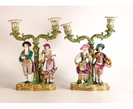 A superb pair of Minton porcelain candelabras, the first modelled as a young couple with baskets of fruit and flowers, the se