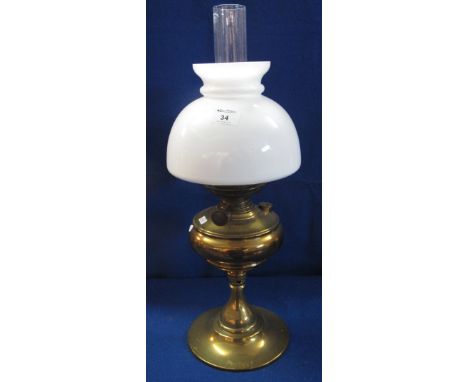 Brass baluster shaped pedestal oil lamp with white glass shade and clear chimney.