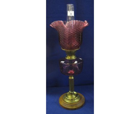 Late 19th Century brass double burner oil lamp with cranberry glass reservoir on brass pedestal base, having moulded cranberr
