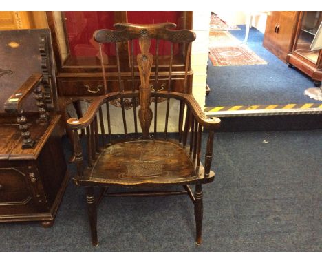 An oak Windsor style stick back arm chair with carved decoration.