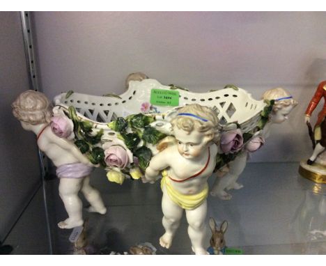 A decorative ceramic bowl held up by cherubs.