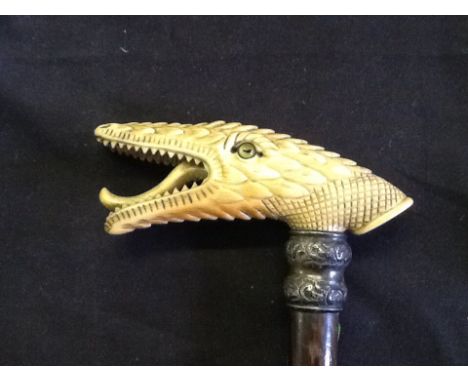 A carved bone snake head with glass eyes walking stick cane with silver collar, damage to wooden cane.