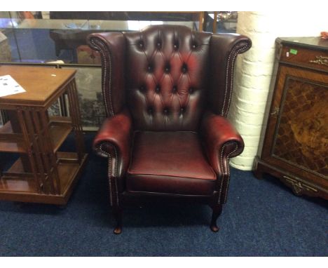 An oxblood winged button backed leather arm chair with stud decoration on mahogany front cabriole legs.