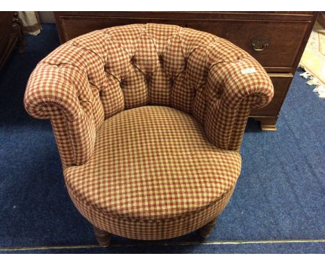 A checked upholstered button back tub chair on mahogany turned support.