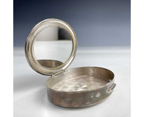 A Steling silver ladies powder compact, of oval section, the hinged lid with engraved monogram and enclosing a mirror, the ba