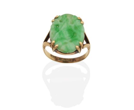 A Jade Ring, an oval jade plaque with carved and pierced floral decoration in a double claw setting, to forked shoulders, fin