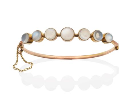 A Moonstone Bangle, seven graduated round cabochon moonstones in milgrain settings, to a knife edge bangle, measures 6cm by 5
