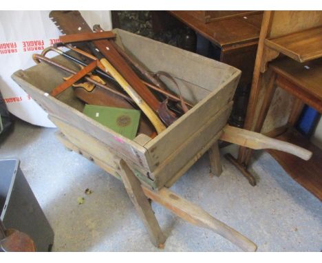 A vintage wheelbarrow containing mixed tools, walking sticks and other items 