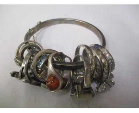 A white metal bangle having mixed rings attached inset with mixed stones 