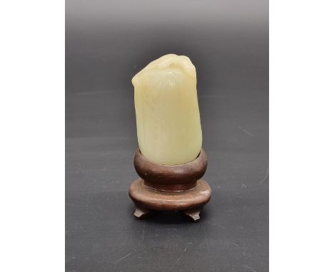 A Chinese carved celadon jade fruit,&nbsp;6.7cm long, on hardwood fitted stand.