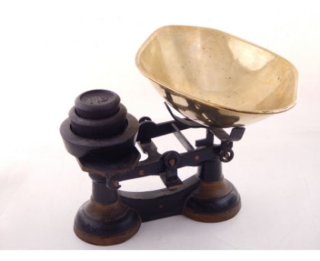 A pair of early 20th century balance scales, cast iron painted black and gilt details, with a brass pan and three weights, to