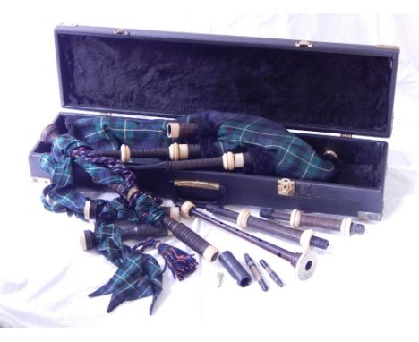 A set of bagpipes, turned wood chanter with ivory and white metal mounts, tartan bag and red tasselled cords, with label 'NE 