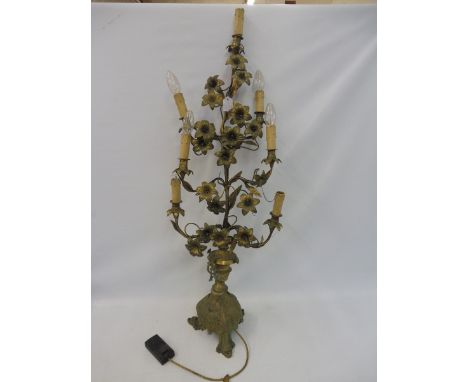 A tall brass table lamp centrepiece in the form of an entwined plant with flowers, raised upon a bold bulbous base on three s