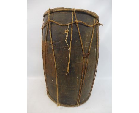 An early, possibly tribal, wooden and rope bound drum with vellum top and bottom, and metal patch repairs, 25" high. 
