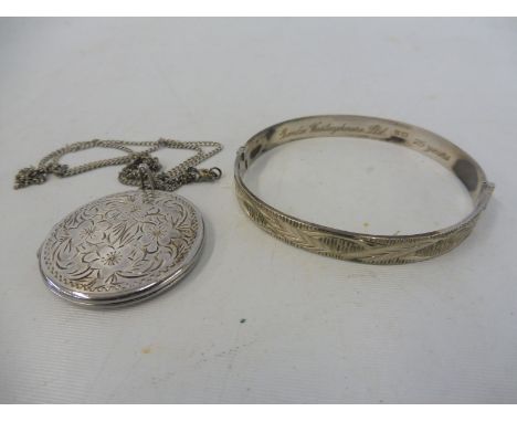 A silver circular locket on chain plus a silver bangle. 