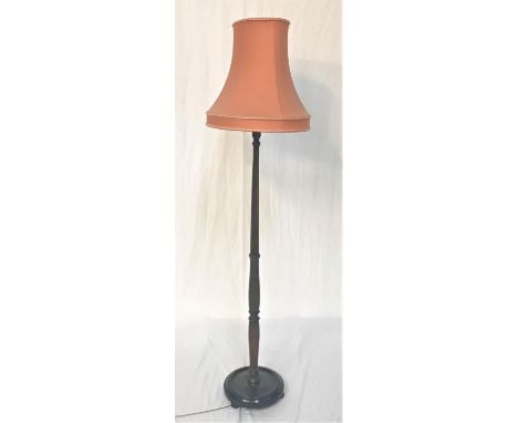 DARK OAK STANDARD LAMP raised on a circular base with flattened bun feet, with a turned column and shaped pink shade, 155cm h