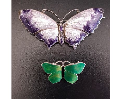 TWO ENAMEL DECORATED SILVER BUTTERFLY BROOCHESthe larger in light and dark purple, 6.2cm wide; the smaller with green wings a