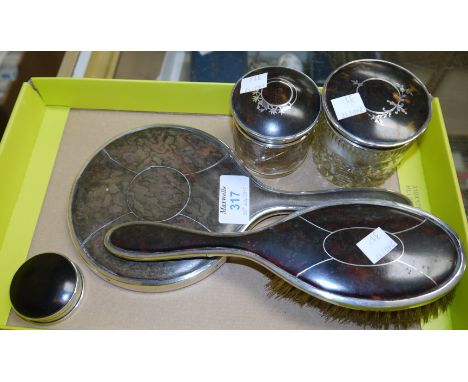 A tortoiseshell and filigree silver dressing table set comprising hand mirror, brush, 2 glass trinket jars, and patch box, va