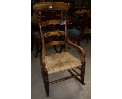 A Victorian country made carved ladder back rush seat rocking arm chair
