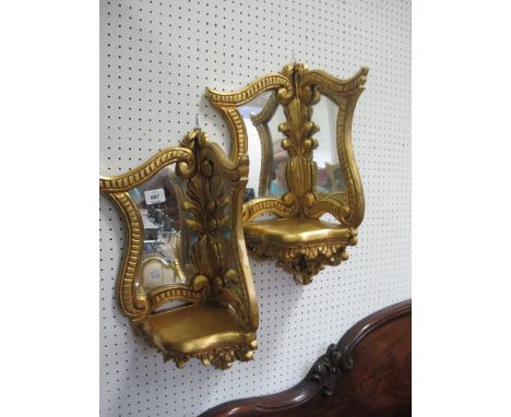 A PAIR OF CONTINENTAL GILTWOOD CORNER WALL BRACKETS the shaped mirror within a foliate moulded frame with serpentine shelf 