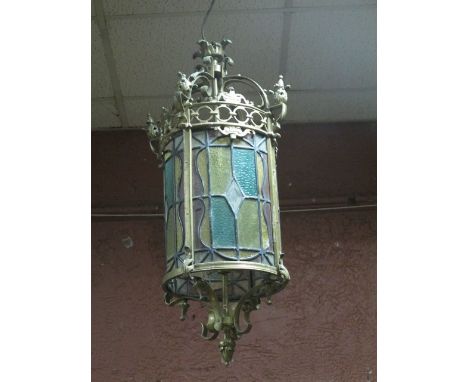 A FINE BRASS LEAD GLASS AND COLOURED GLASS SINGLE LIGHT HALL LANTERN of cylinderical form with pierced circlet with styized f