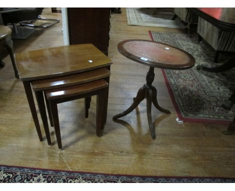 A MAHOGANY WINE TABLE the oval top with tooled leather inset raised on tripod support together with a nest of three mahogany 