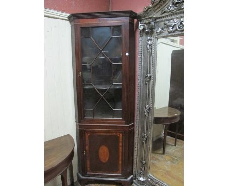 A GEORGIAN MAHOGANY AND SATINWOOD CROSS BANDED CORNER CABINET the moulded cornice above an astragal glazed door the base with