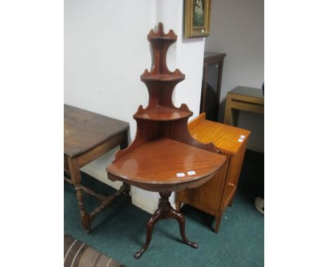 A MAHOGANY CORNER TABLE the superstructure with four graduated shelves of demilune outline above a baluster column on tripod 