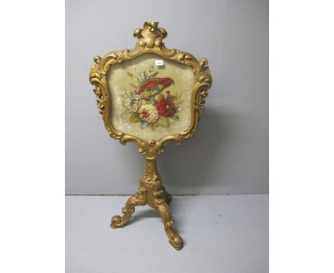 A VICTORIAN CARVED GILTWOOD FIRESCREEN of cartouche outline the needlework panel depicting exotic birds and flowerheads raise