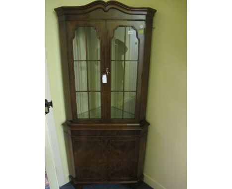 A GOOD WALNUT CORNER CABINET the moulded cornice above astragal glazed doors the base with cupboards between canted angles on