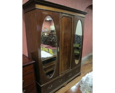 AN EDWARDIAN MAHOGANY WARDROBE the outset moulded cornice above a central recessed panel flanked on each side by oval bevelle